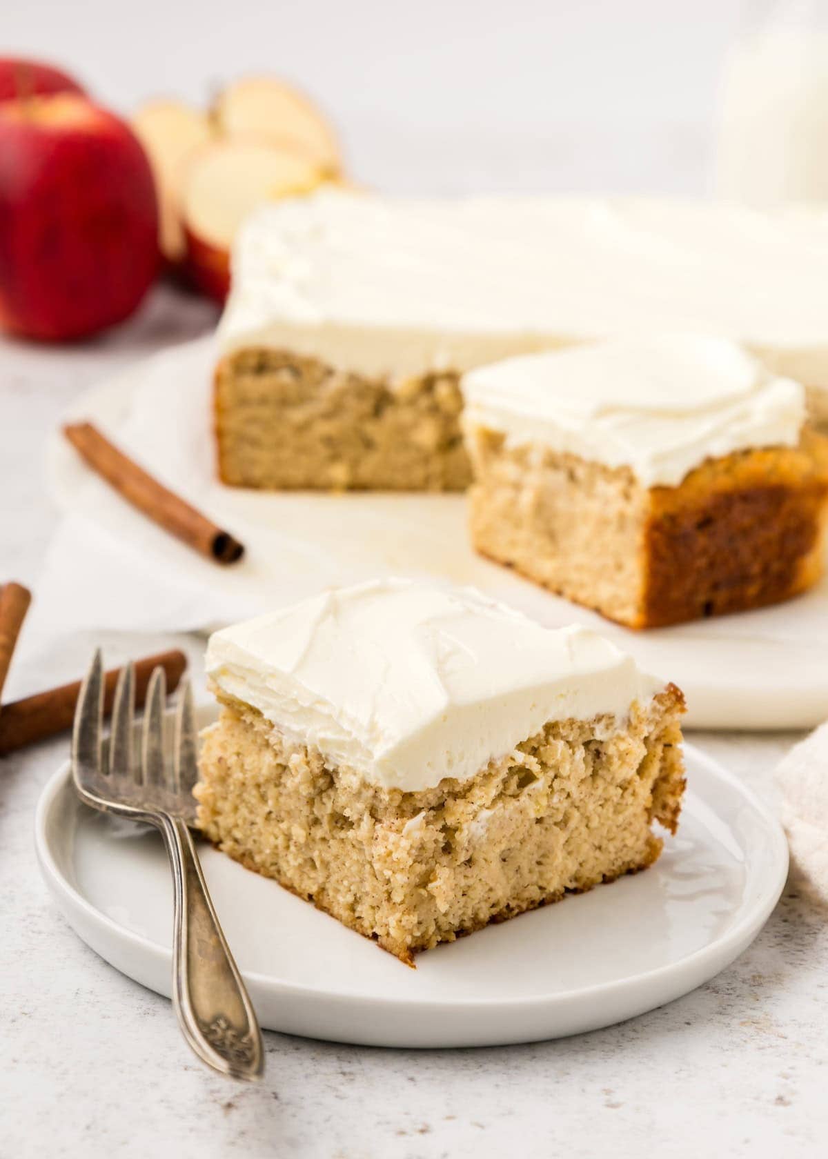 A slice of applesauce cake topped with white frosting on a small dessert plate.