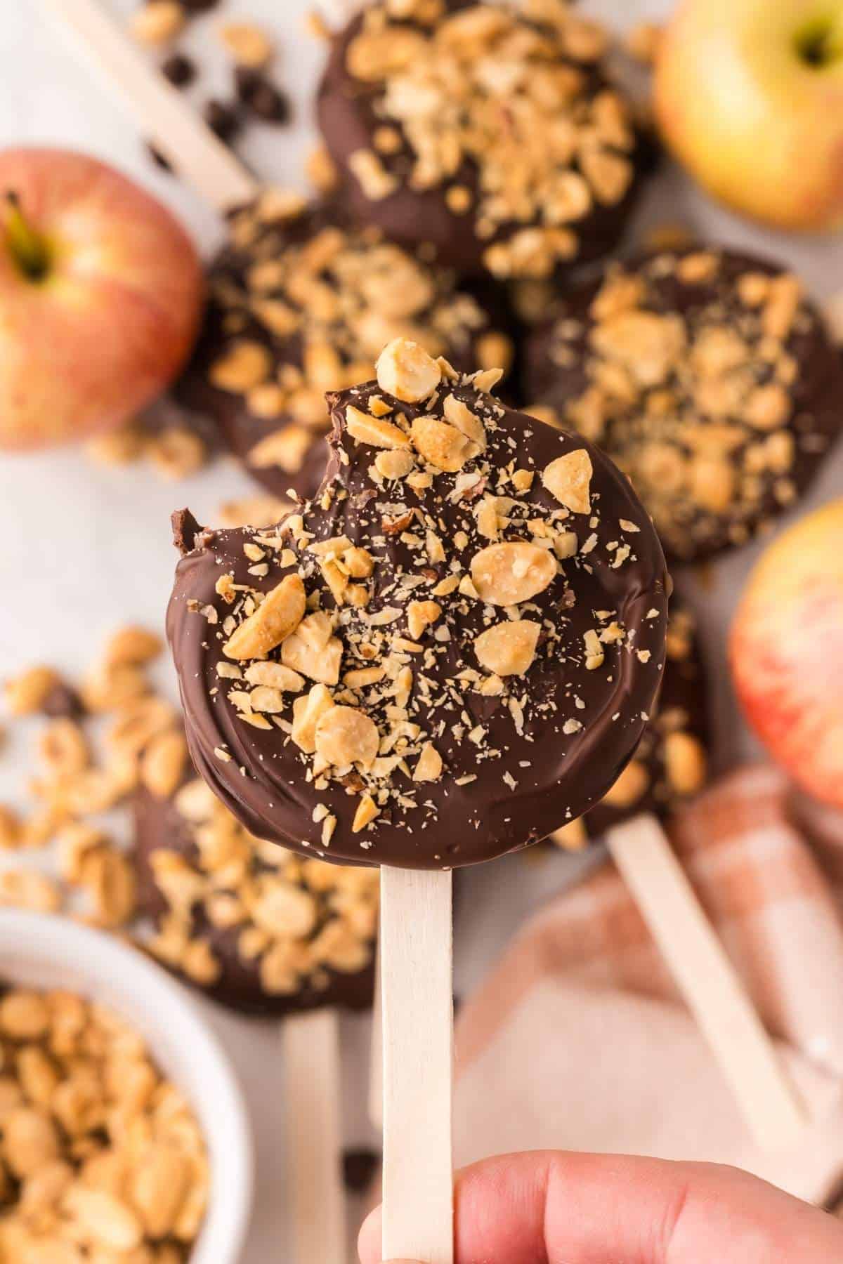 Several chocolate caramel apple pops laying on a table.