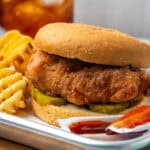 A homemade chick fil a sandwich served with waffle fries and sauce.