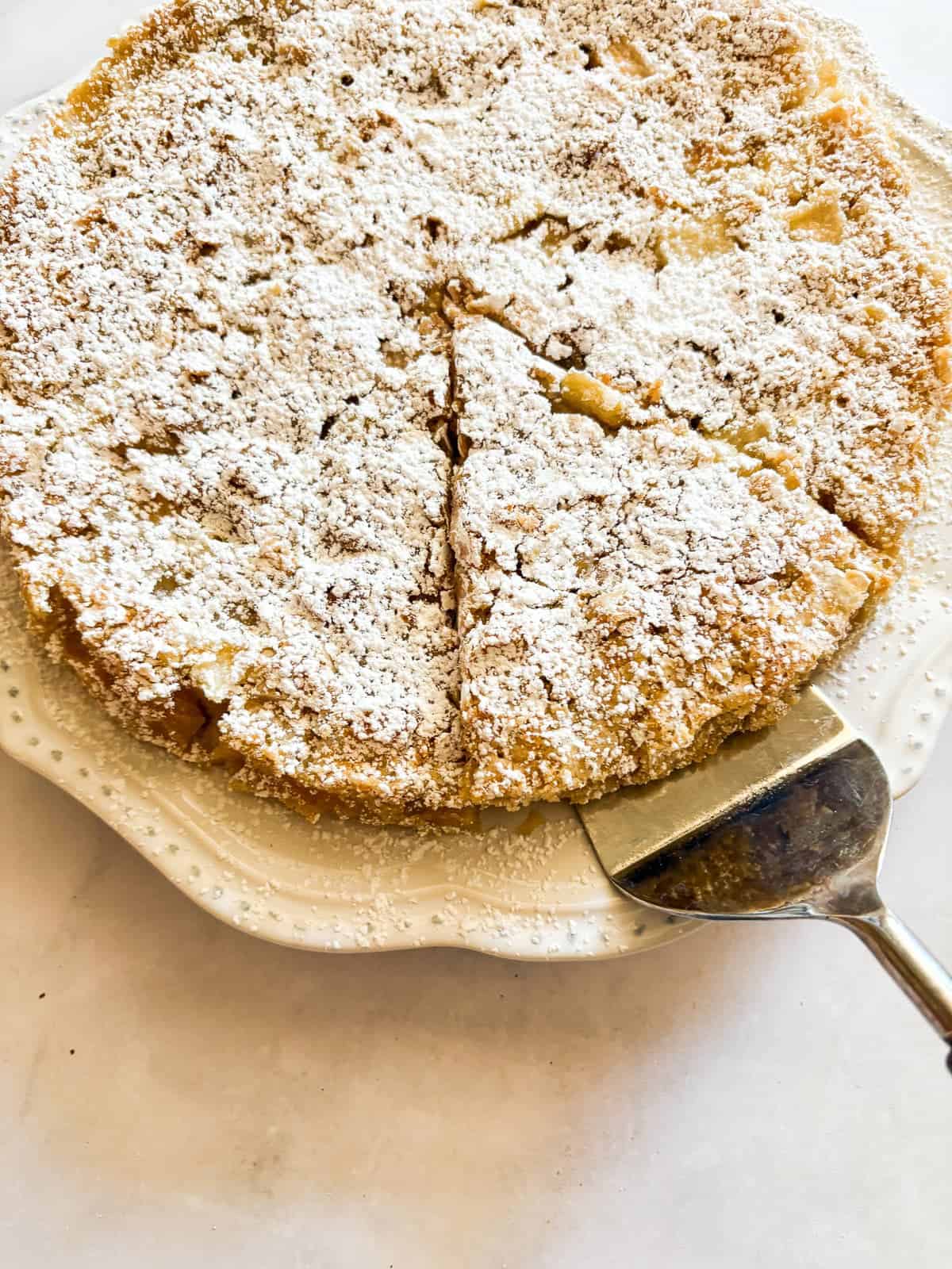 A slice of french apple cake being lifted with a cake server.