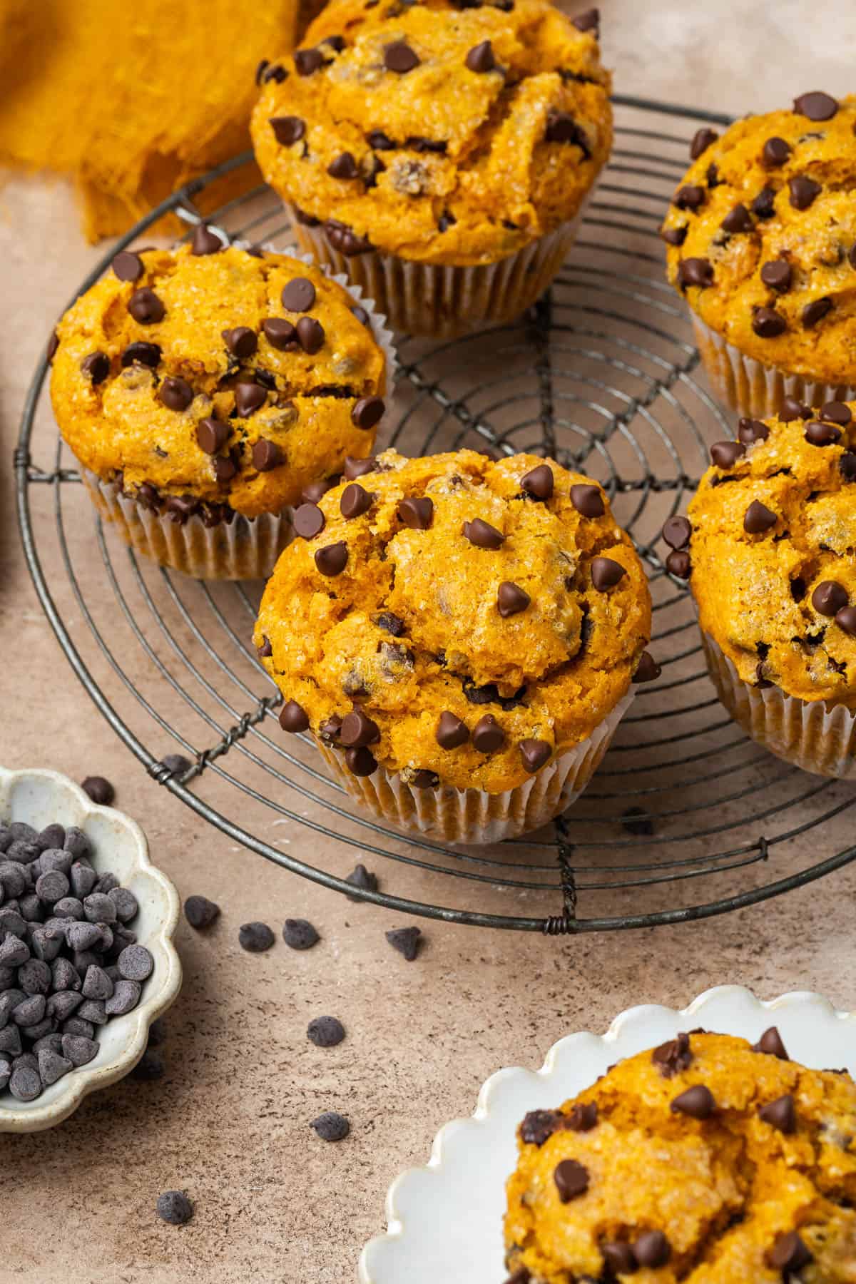 A batch of gluten free pumpkin chocolate chip muffins cooling on a wire rack. 