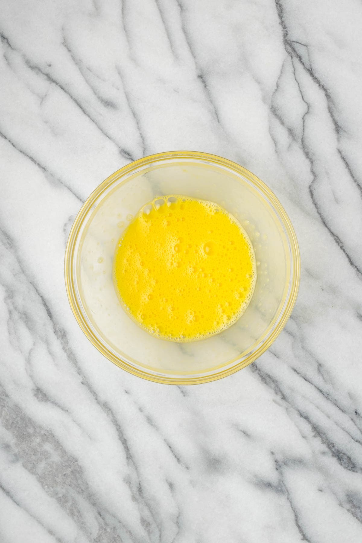 An egg beaten in a small bowl. 