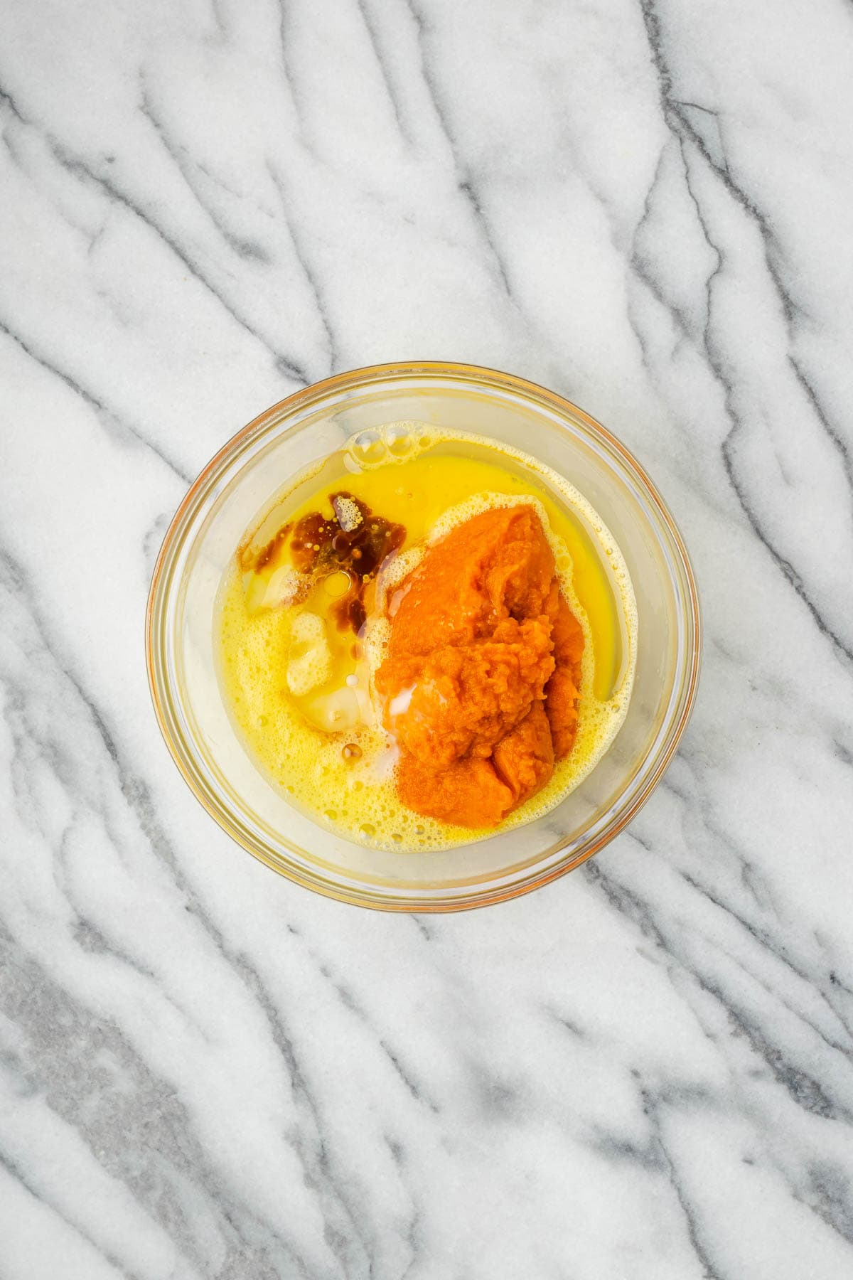 Pumpkin puree, oil, vanilla, and milk added to the bowl with the beaten egg.