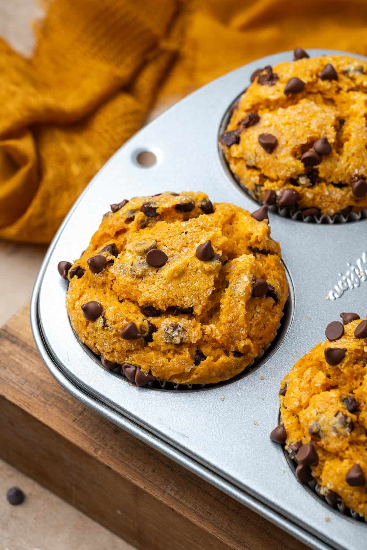 Freshly baked pumpkin chocolate chip muffins in a metal pan.