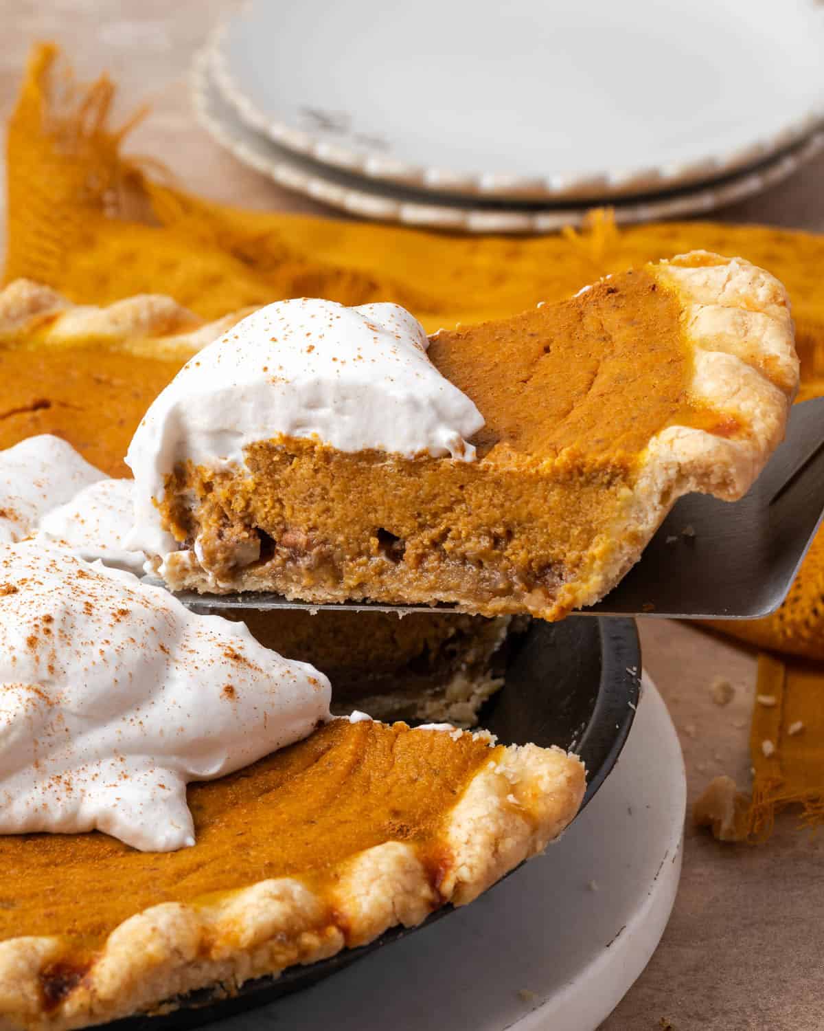 A slice of gluten free pumpkin pie being lifted from a pie plate.