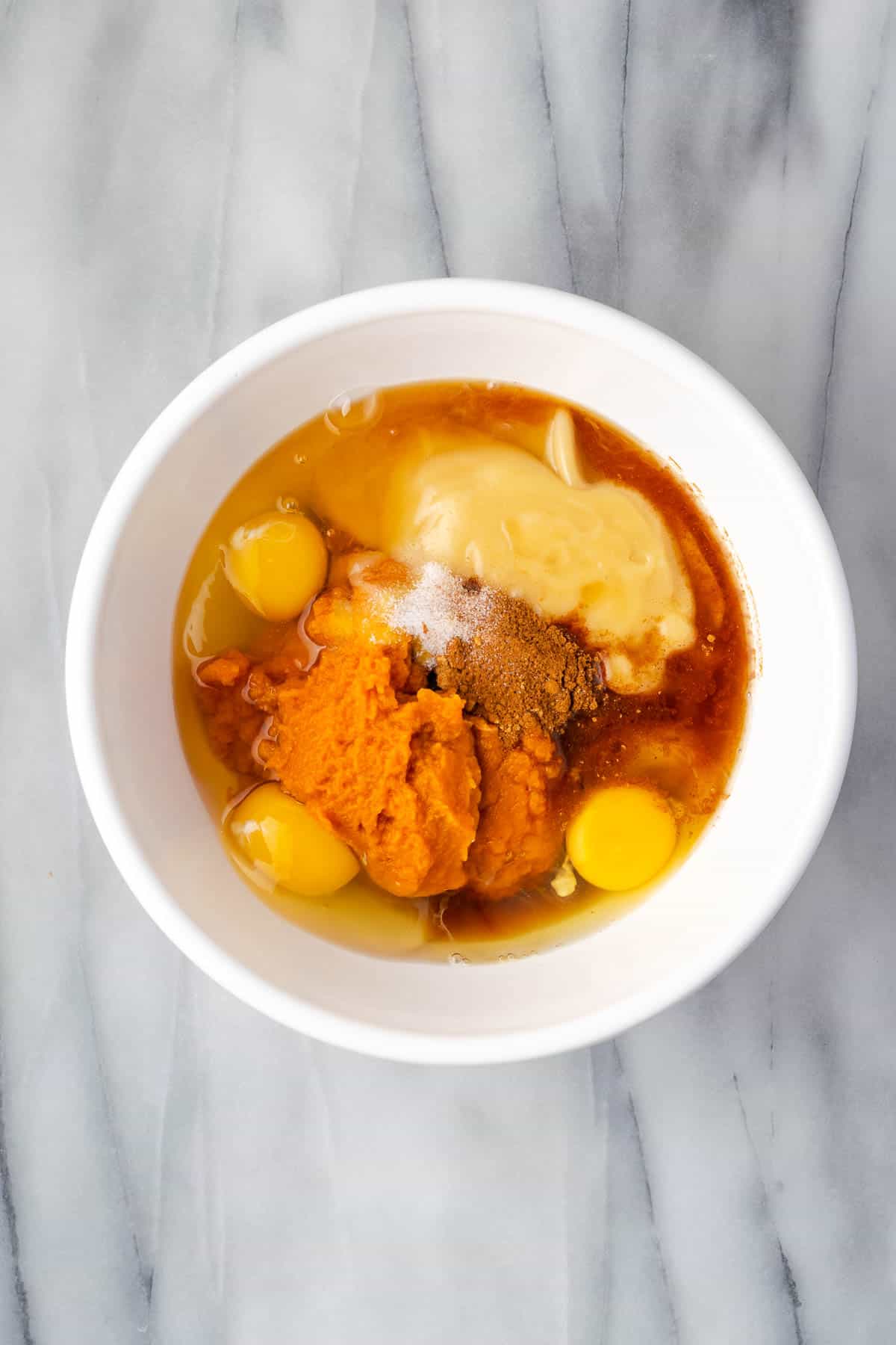 Pumpkin puree, eggs, sweetened condensed milk, bourbon, maple syrup, salt and spices combined in a large mixing bowl. 
