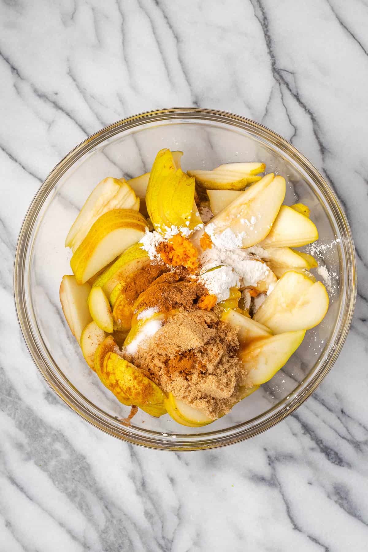 Orange juice, orange zest, honey, brown sugar, cornstarch, cinnamon, nutmeg and salt added to the bowl with the sliced pears.