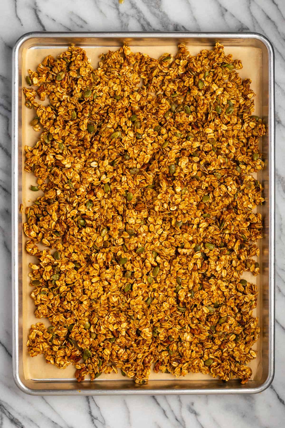Unbaked pumpkin granola on a large baking sheet. 