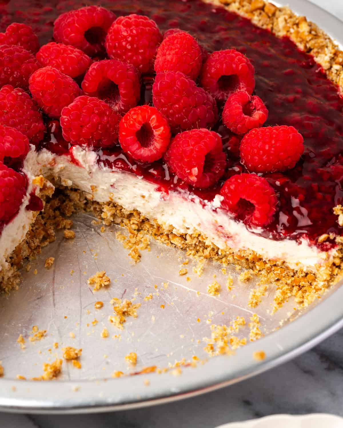 A raspberry cream pie with a pretzel crust sitting on a kitchen counter.
