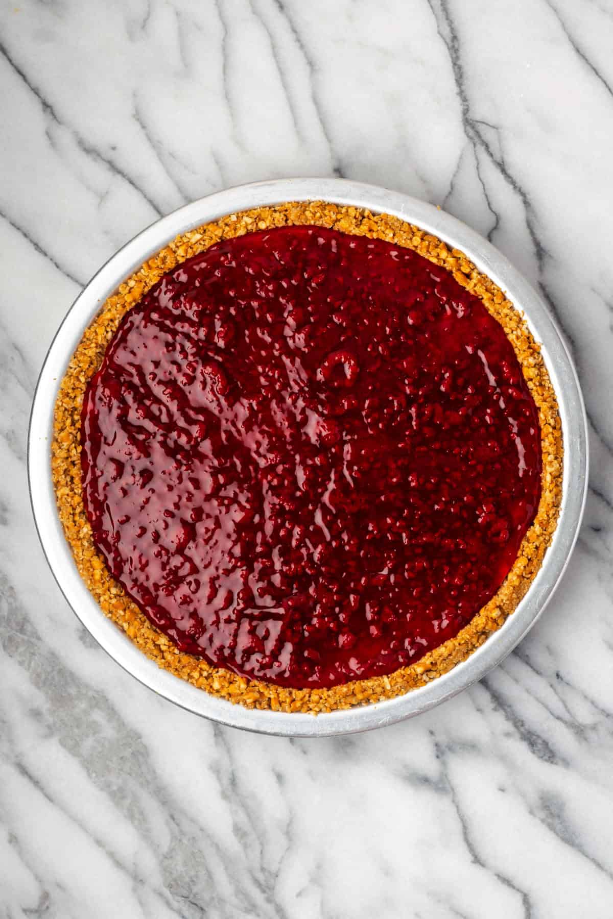 Raspberry pie filling spread on top of the cheesecake pie.