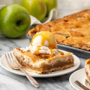A slice of an apple slab pie topped with ice cream served on a small dessert plate.