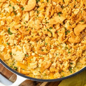 A broccoli rice casserole topped with crushed crackers sitting on a wood tray.