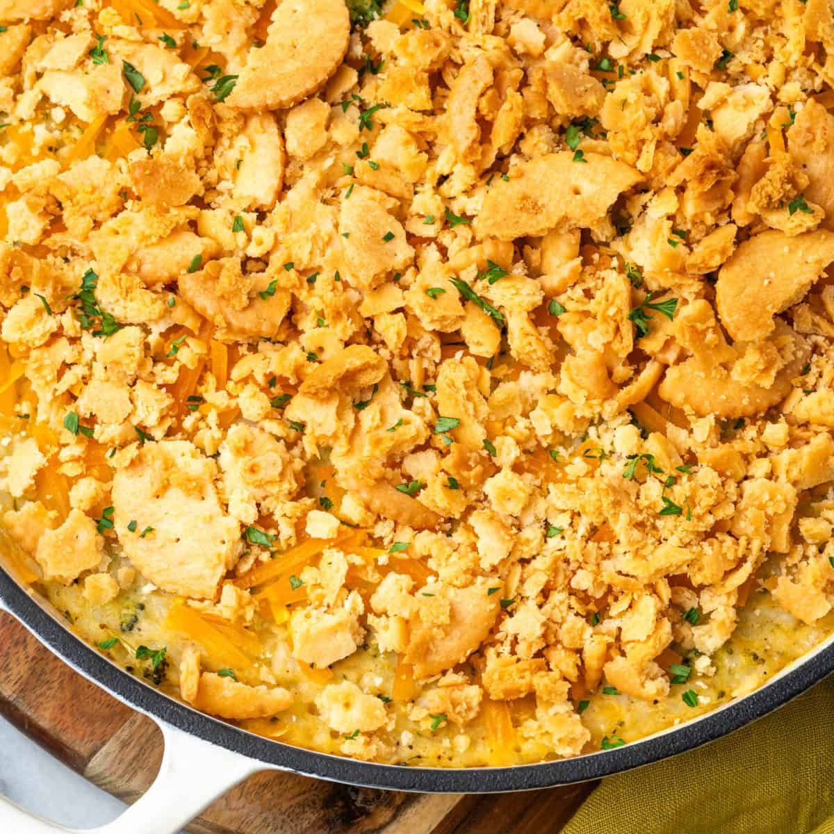 A broccoli rice casserole topped with crushed crackers sitting on a wood tray.