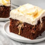 A slice of chocolate caramel poke cake served on a small dessert plate.