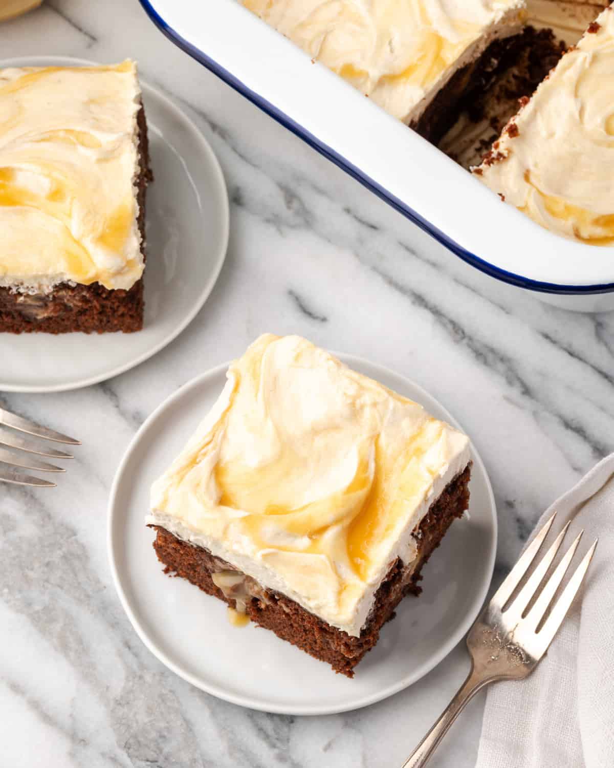 Slices of chocolate caramel poke cake served on two small dessert plates. 
