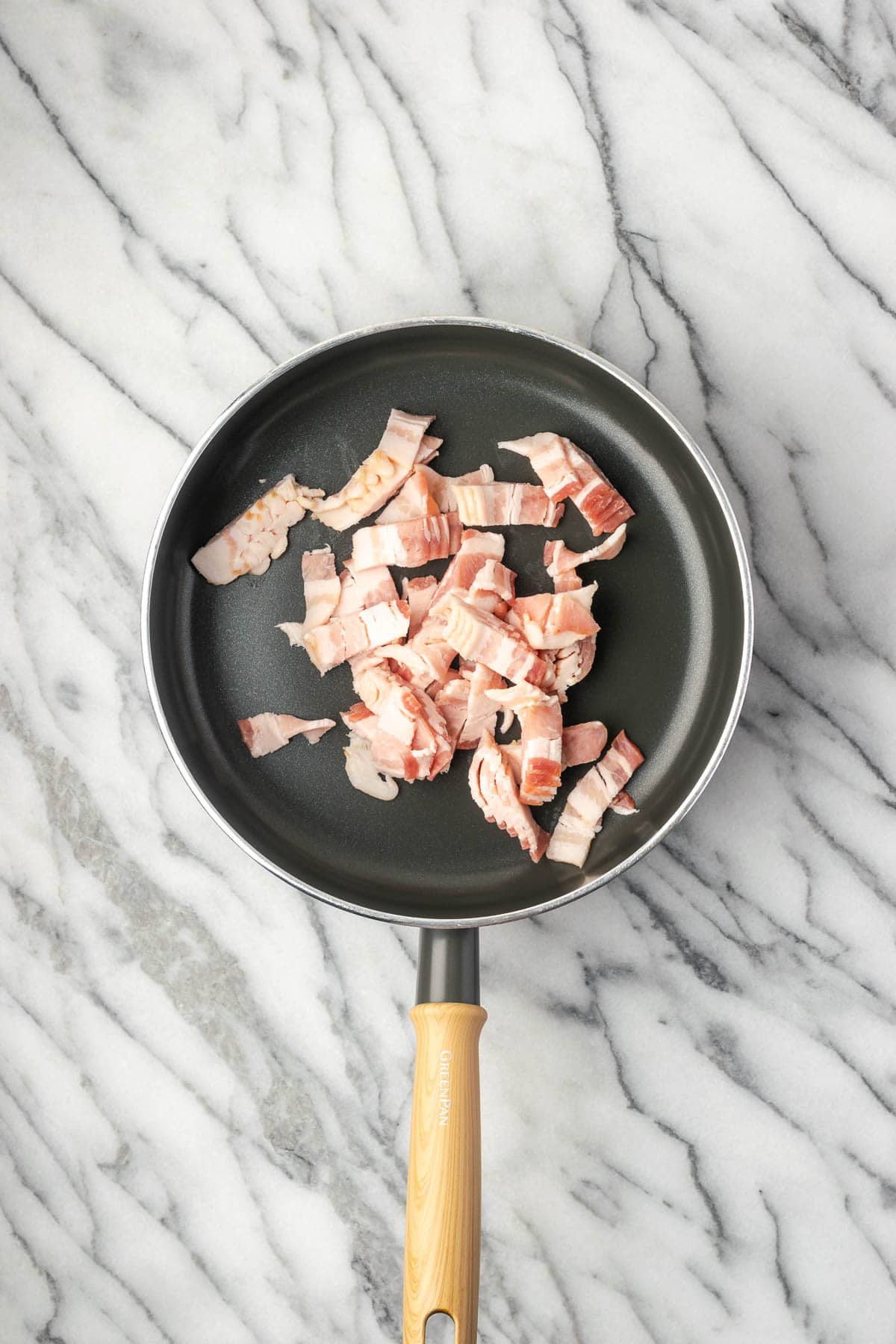 Bacon pieces cooking in a non stick saucepan.
