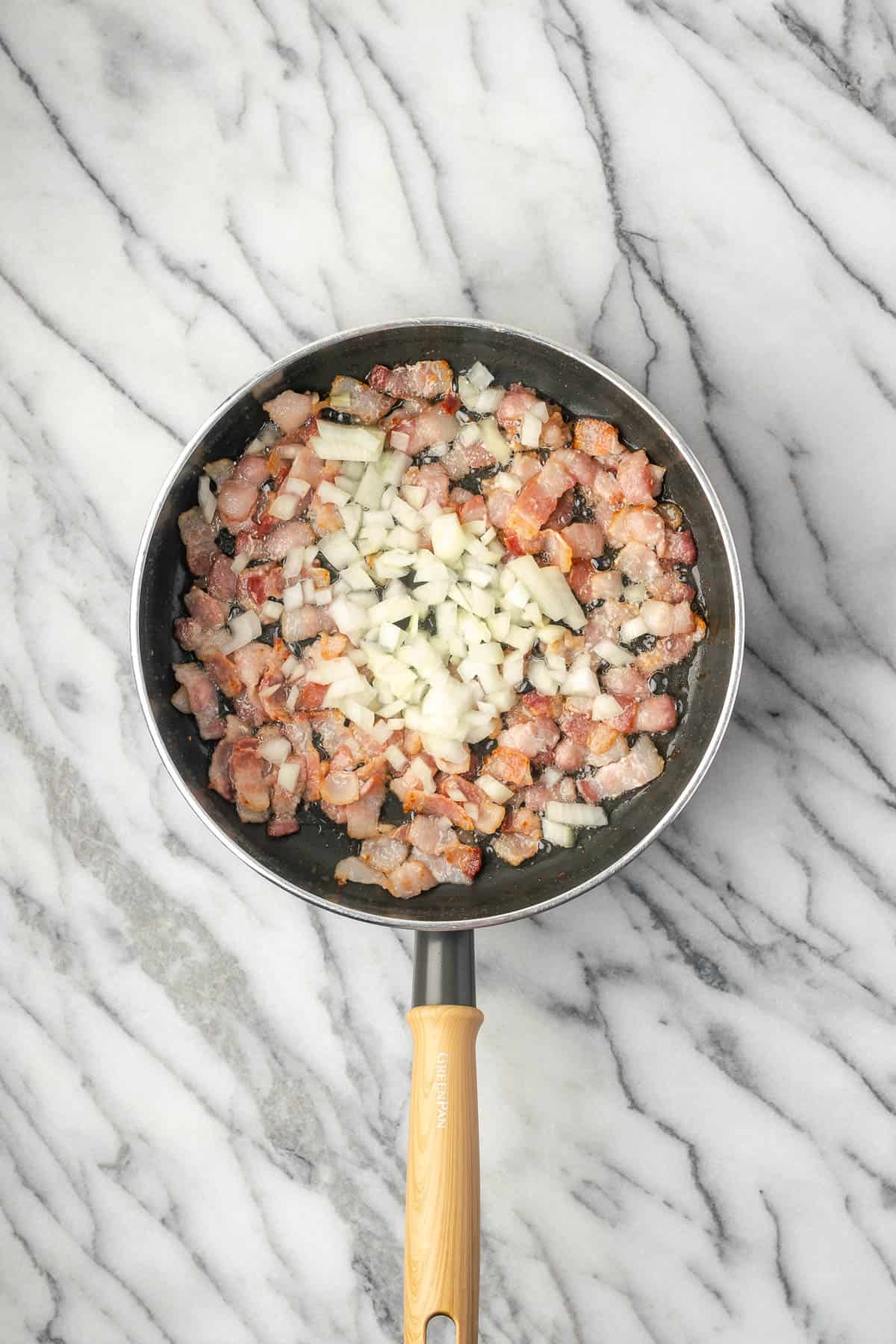 Diced onion added to the pan with the cooking bacon.