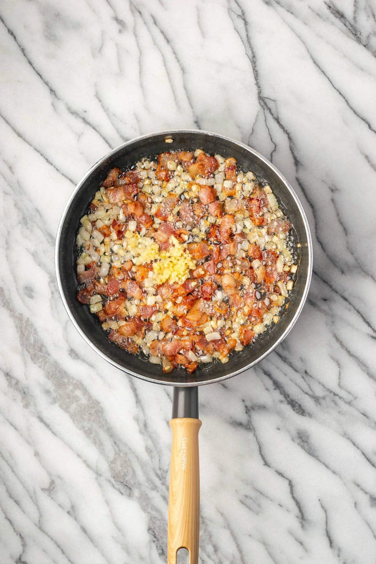 Minced garlic being added to the bacon and onions.