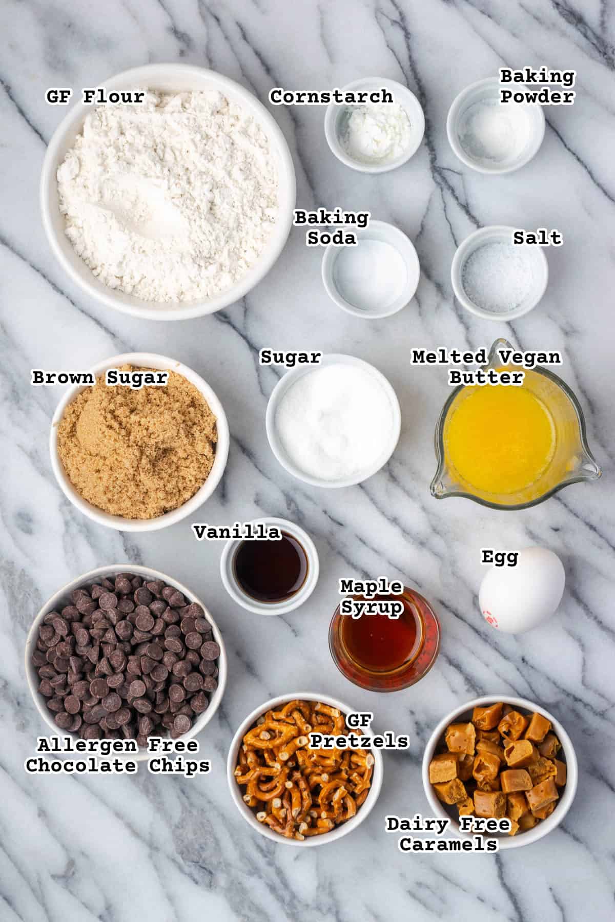 Ingredients for caramel pretzel chocolate chip cookies sitting on a marble counter.