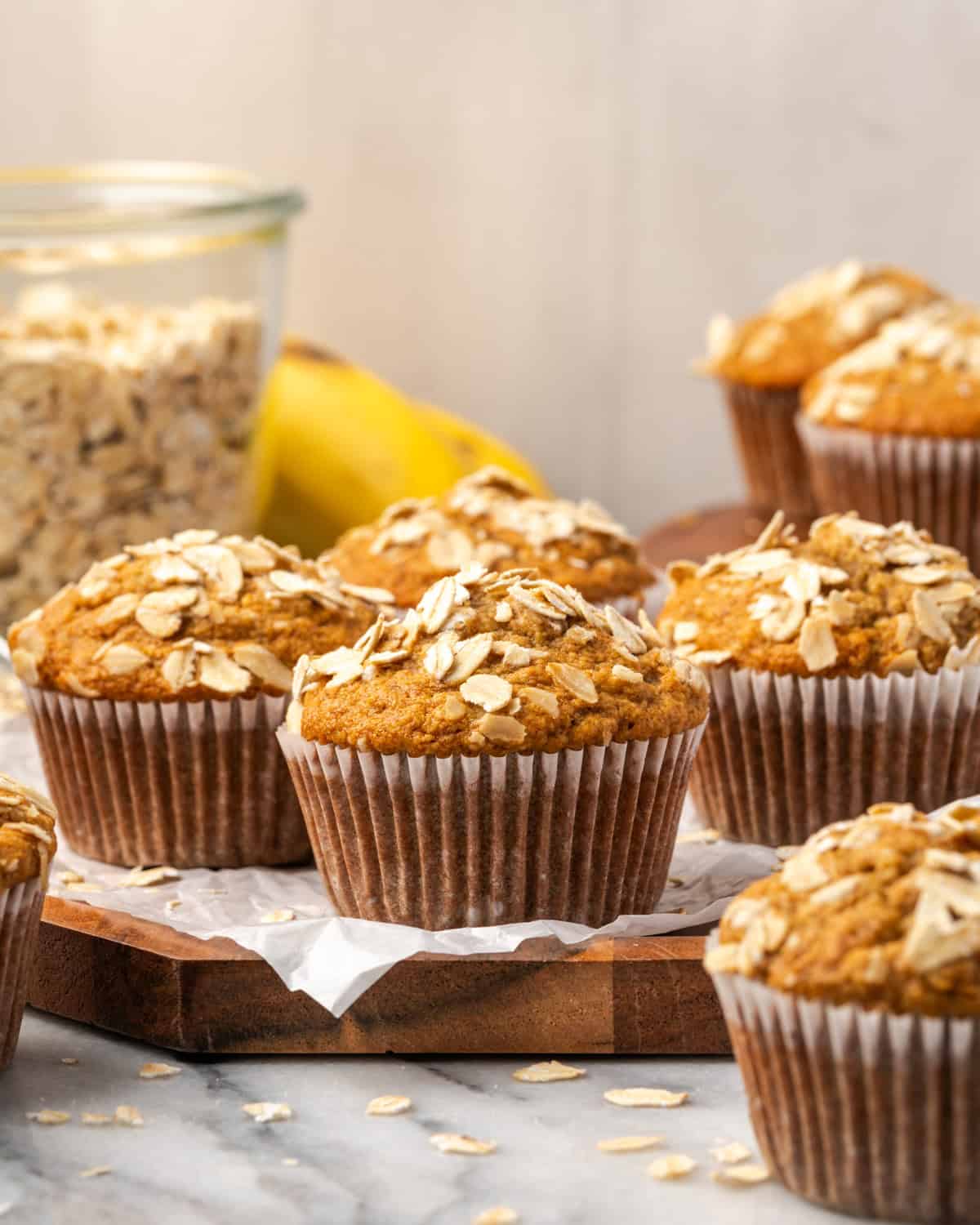 A batch of oat flour banana muffins sitting on a wood tray.