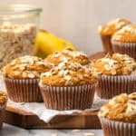 Several banana oat flour muffins sitting on a wooden tray.