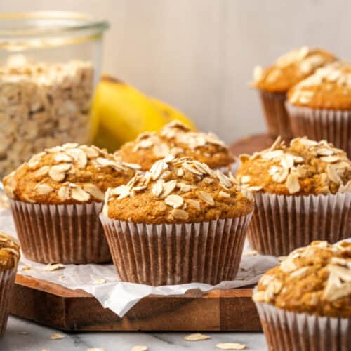 Several banana oat flour muffins sitting on a wooden tray.