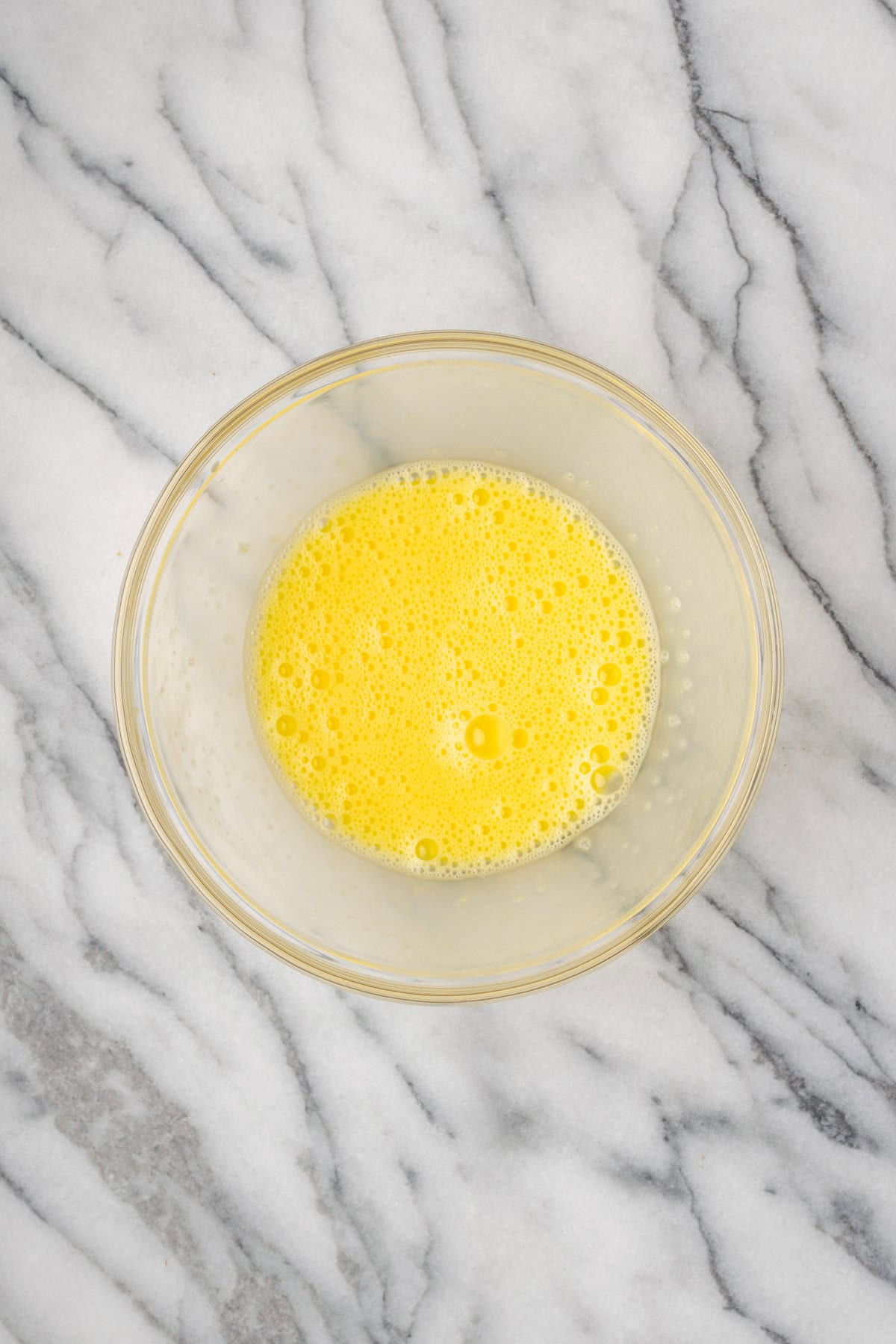 Beaten eggs in a small glass bowl.