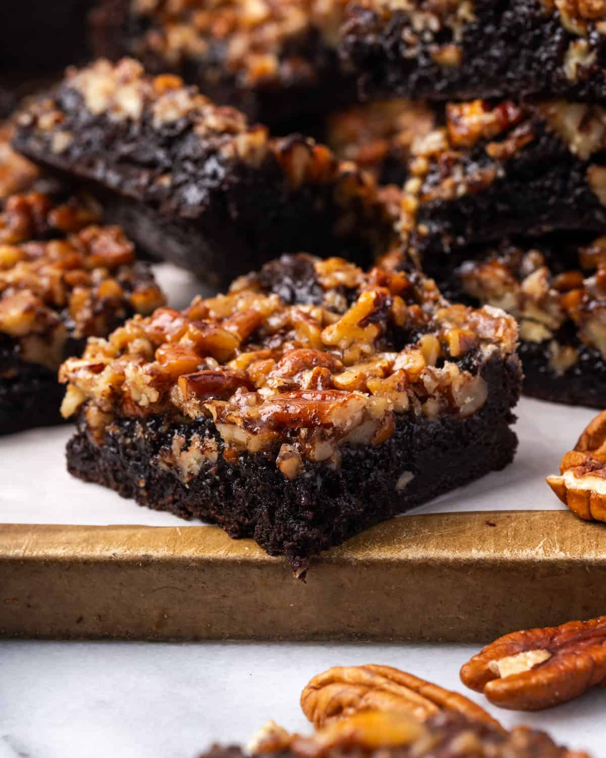 Several pecan pie brownies sitting on a wooden cutting board.
