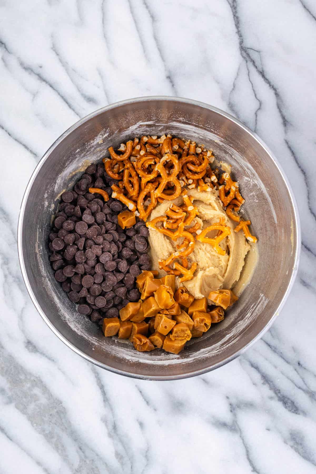 Chocolate chips, pretzel pieces and caramels added into the bowl with the cookie dough.