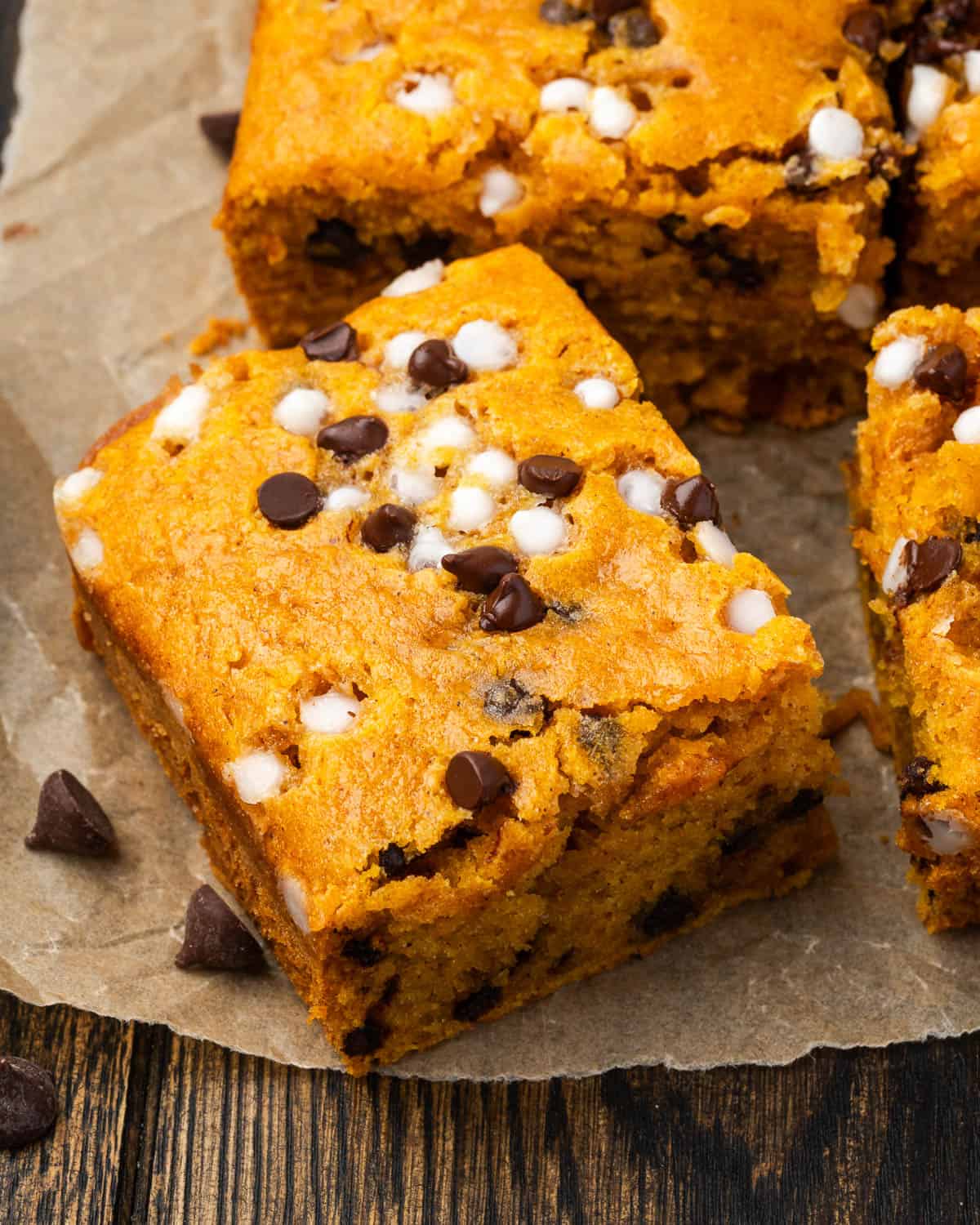 Several slices of pumpkin chocolate chip cake sitting on a wood table.