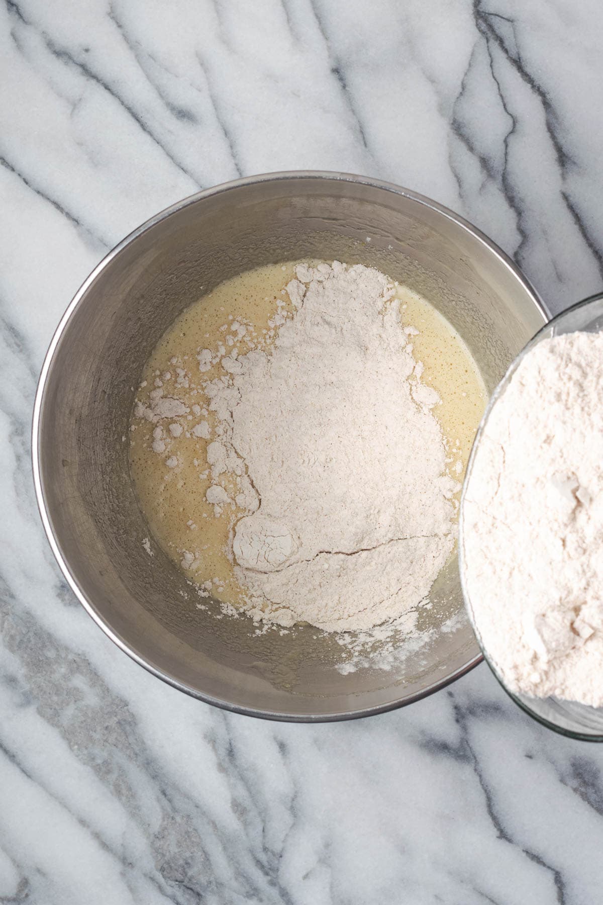 Dry ingredients being poured into the bowl with the wet ingredients.