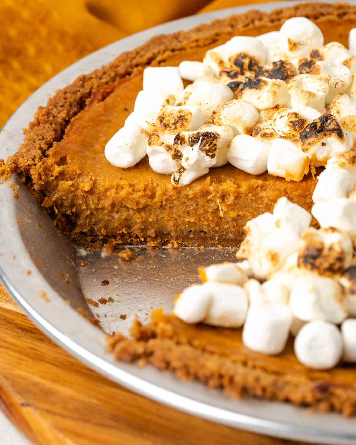 A marshmallow topped sweet potato pie with a slice taken out. 