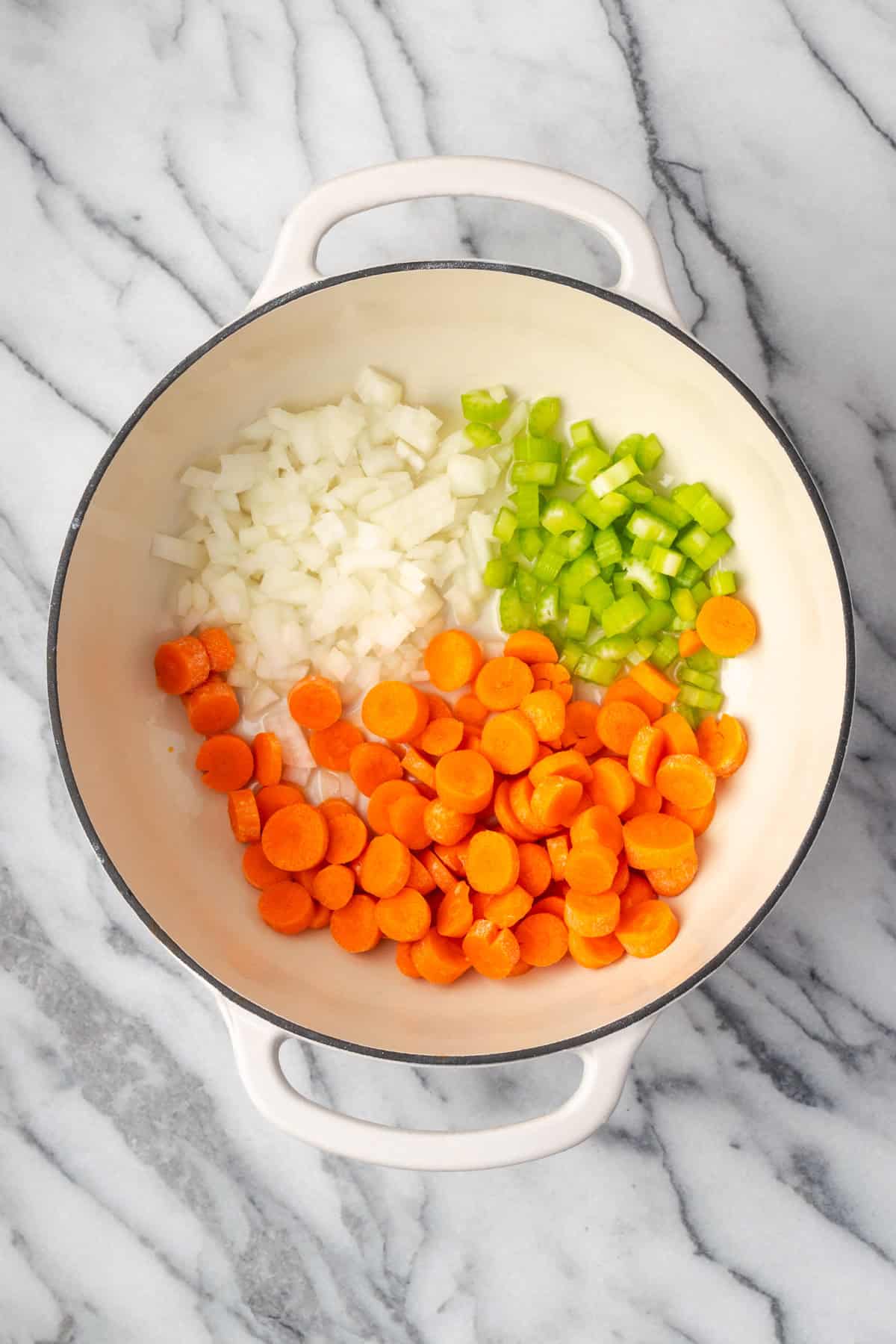 Carrots, onions and celery being sauteed in a large soup pot.