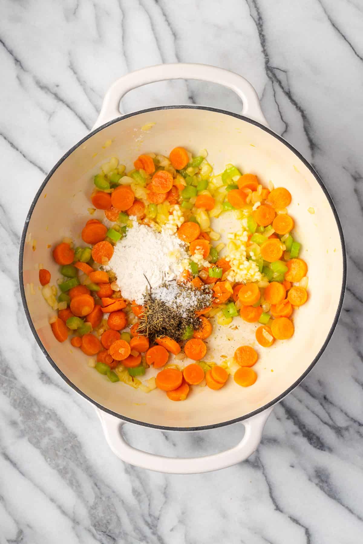 Minced garlic, flour, herbs and spices added to the pot with the partially cooked vegetables.