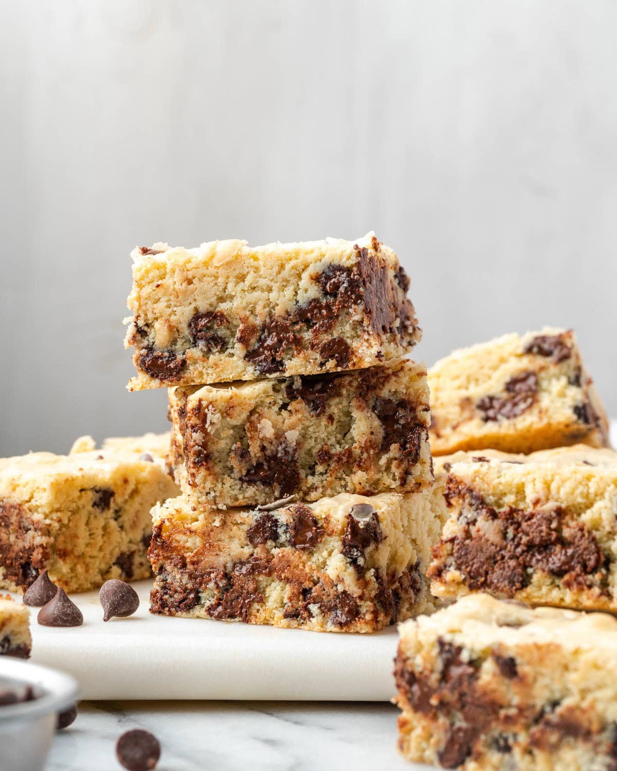 A stack of three white chocolate blondies sitting on a marble serving board. 