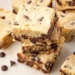 A stack of three white chocolate blondies sitting on a marble board.