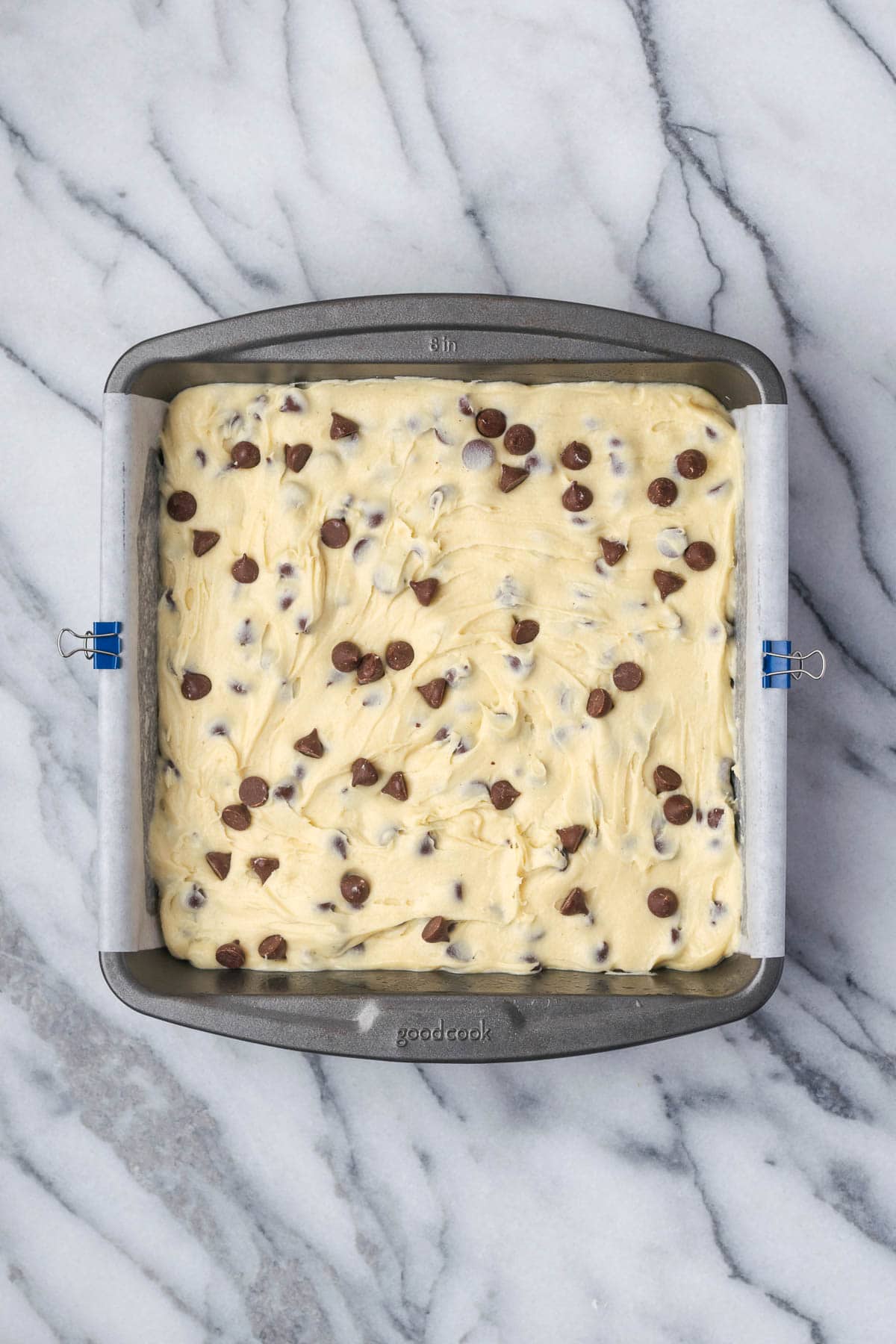 A pan of unbaked white chocolate blondies sitting on a marble counter. 