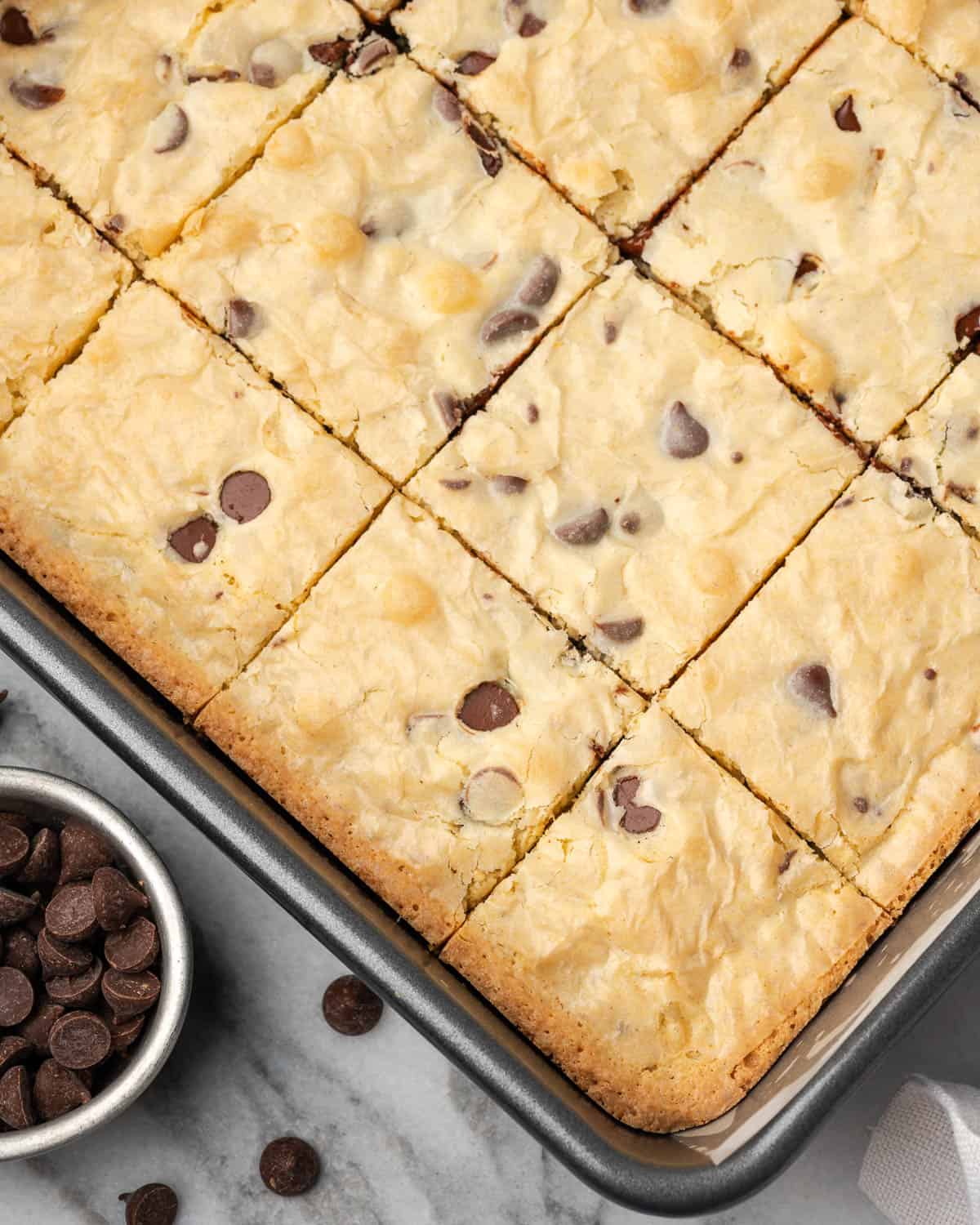 A pan of freshly baked white chocolate blondies sitting on a marble counter.