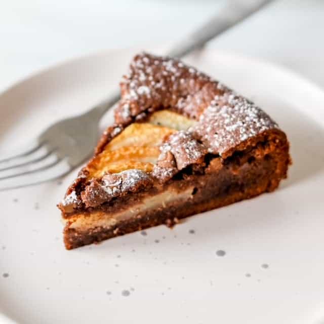 A slice of a chocolate pear tart served on a small plate.