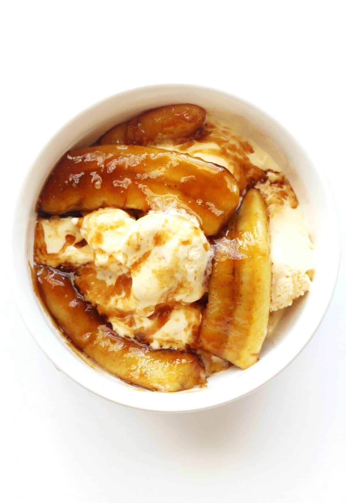 A bowl of bananas foster served over ice cream.