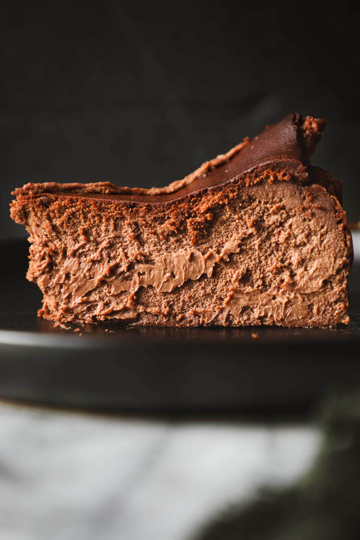 A slice of chocolate basque cheesecake sitting on a serving plate.