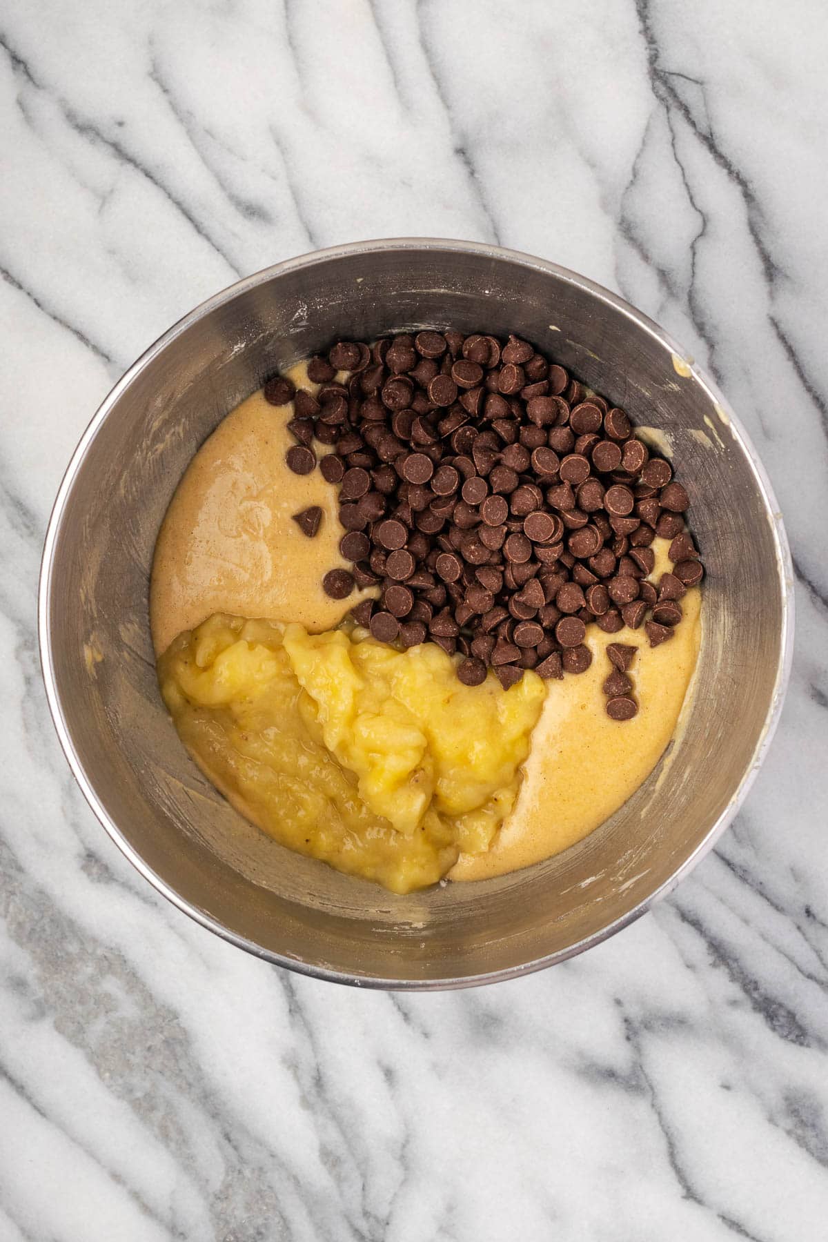 Mashed bananas and chocolate chips being stirred into the cake batter. 
