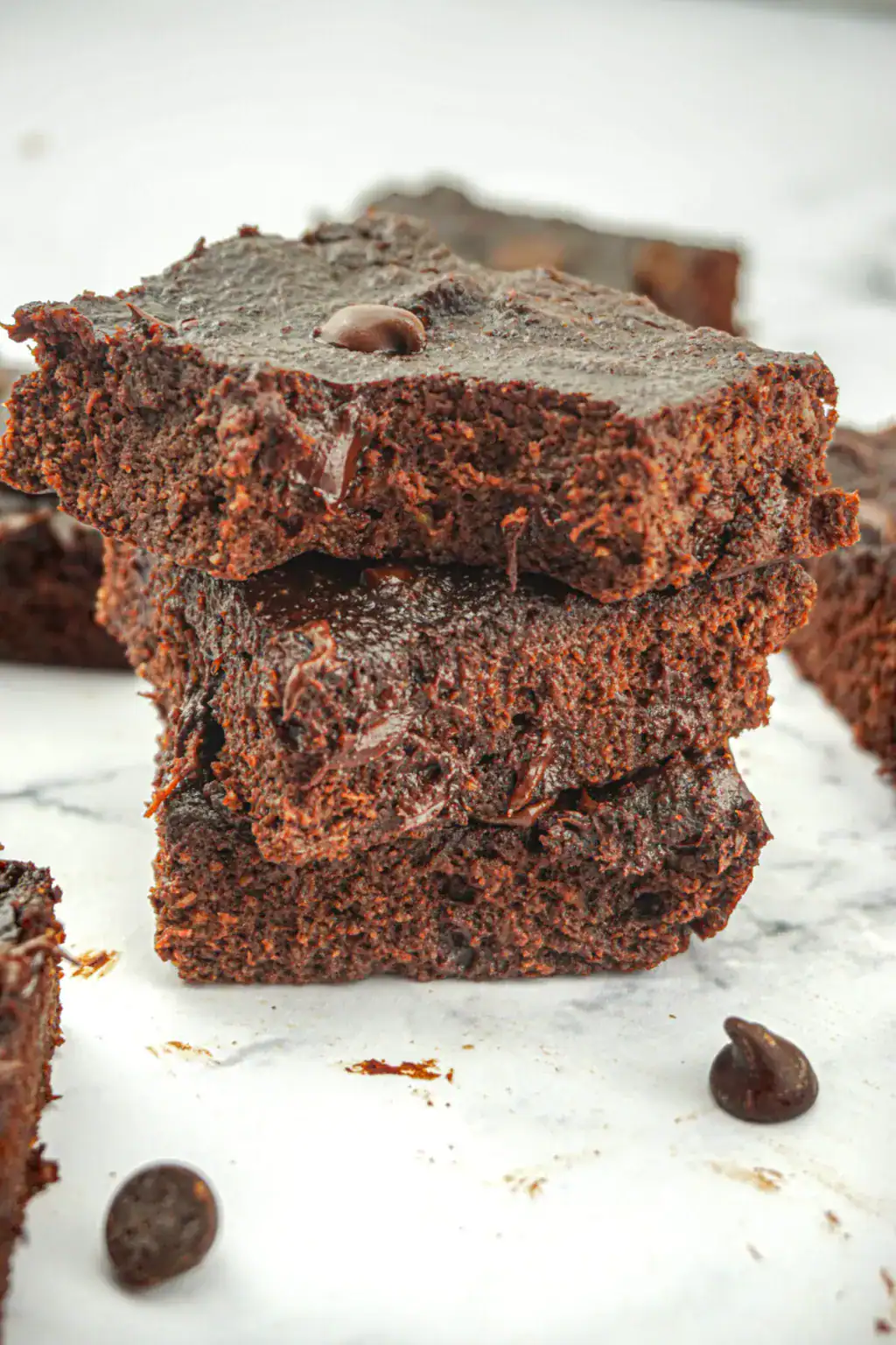 a stack of three gluten free chocolate banana brownies on a white counter.