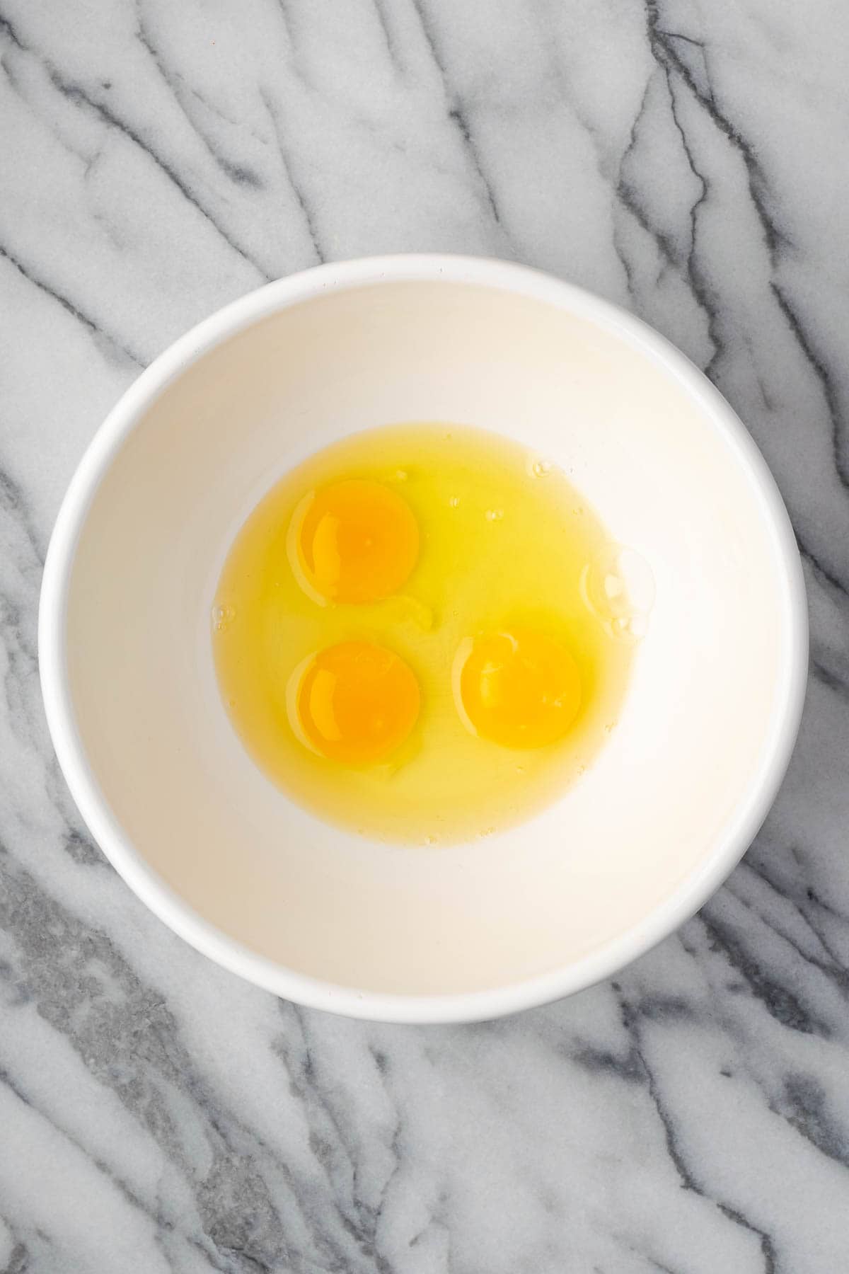 Three eggs in a large mixing bowl.