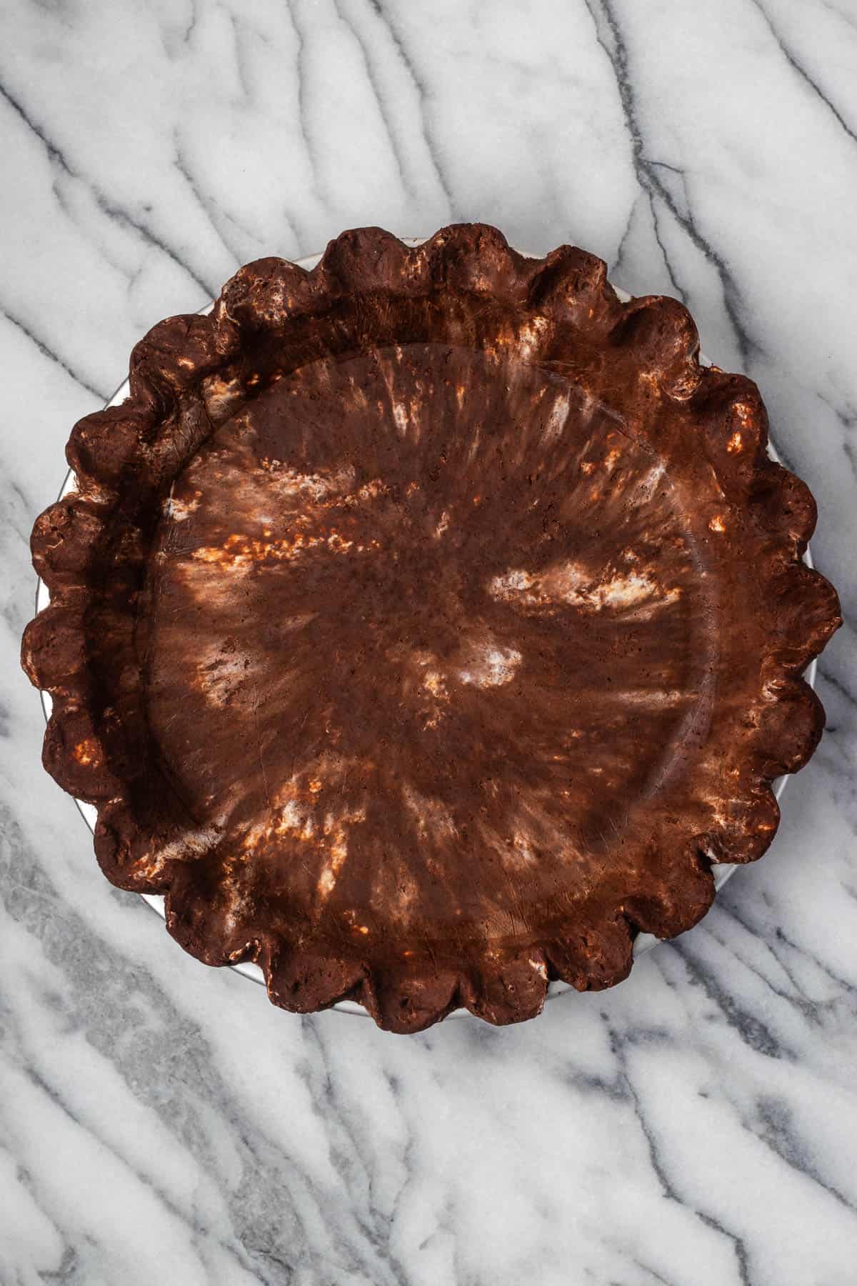 An unbaked chocolate pie shell sitting on a marble counter.