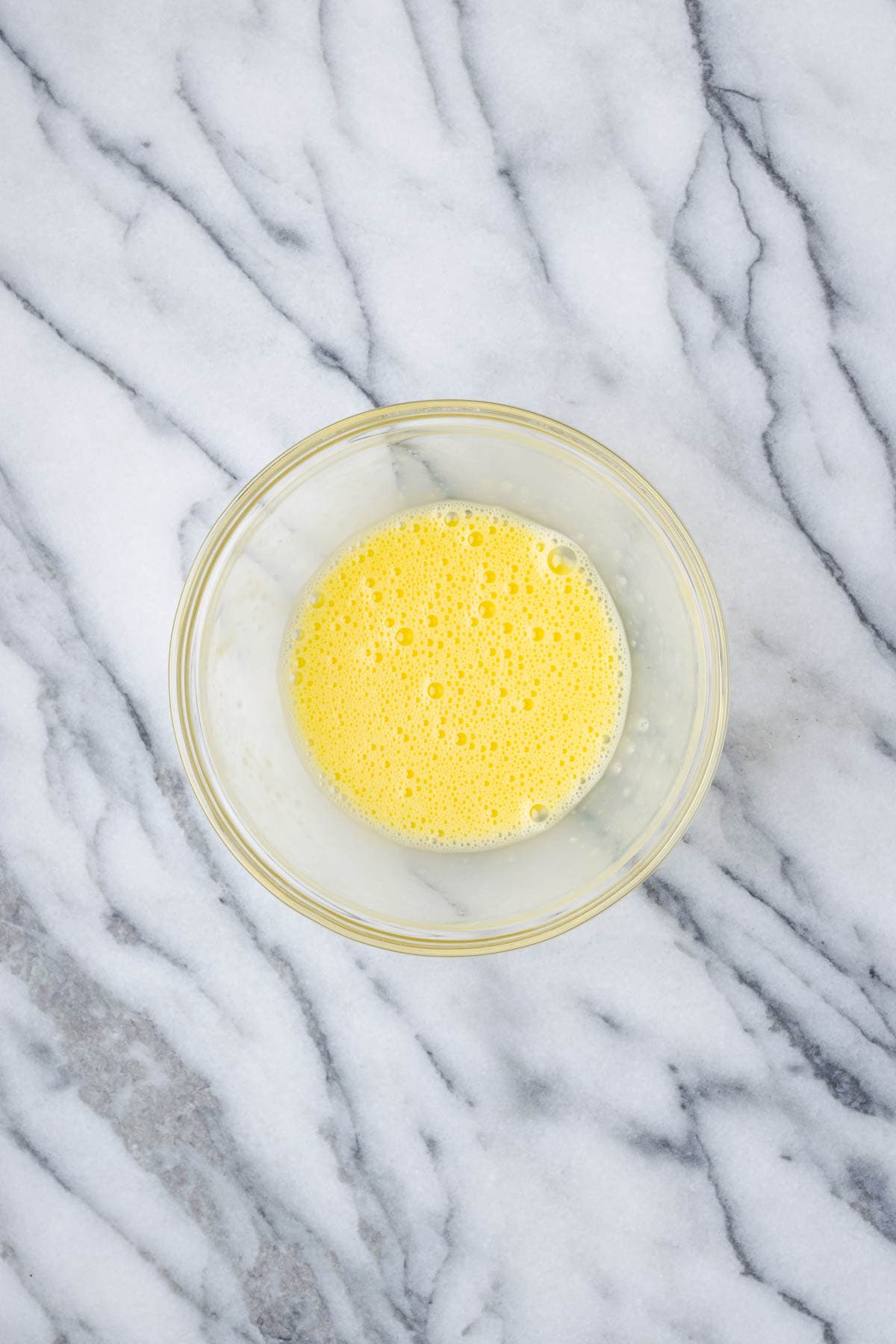 A beaten egg in a small glass bowl.