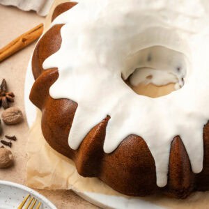 a gingerbread bundt cake topped with white chocolate ganache sitting on a marble tray.
