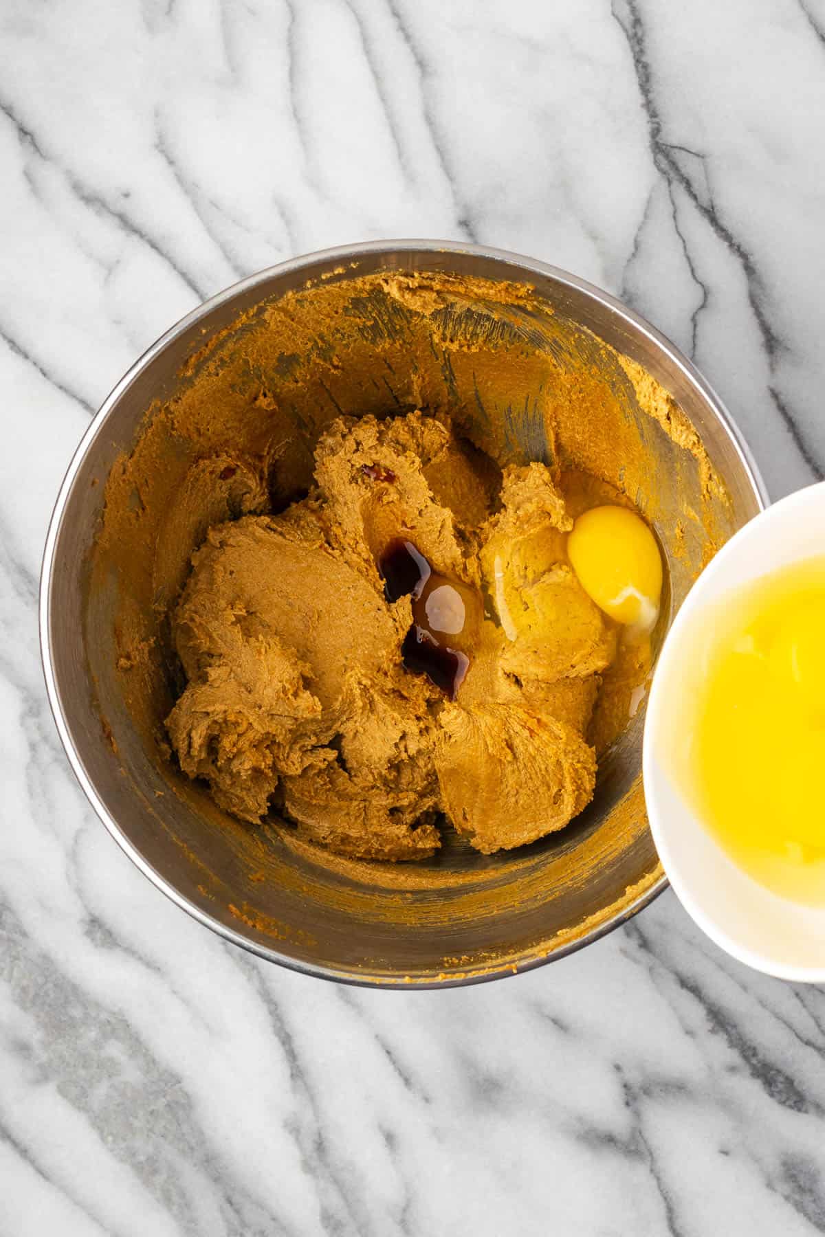 Vanilla and eggs being added into the partially mixed cake batter.