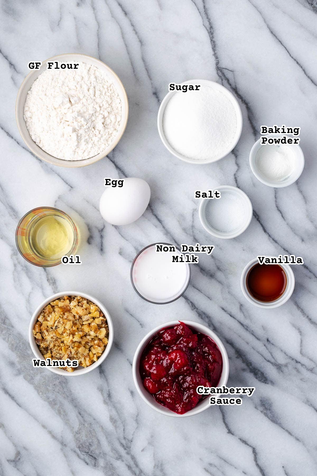 Ingredients for cranberry sauce muffins on a marble counter.