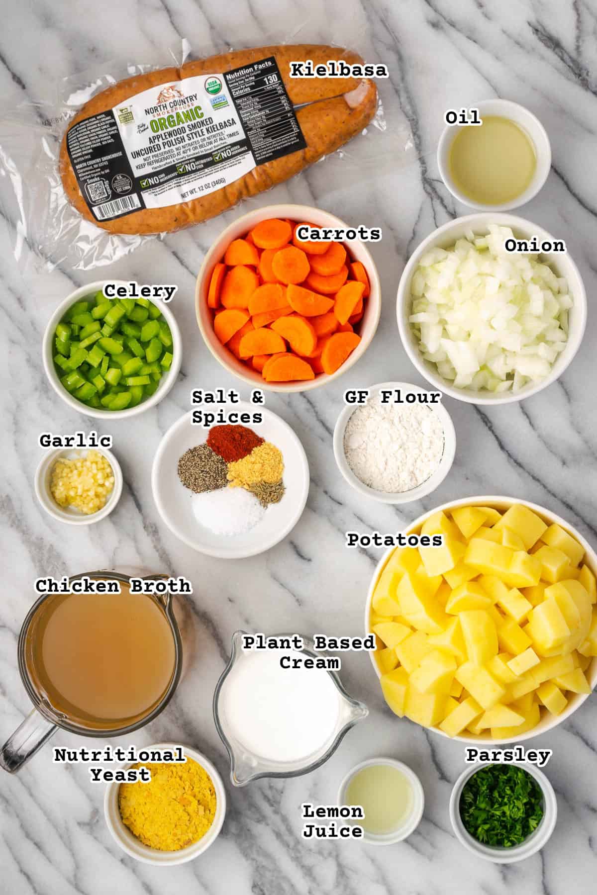 Ingredients for kielbasa potato soup sitting on a marble countertop. 
